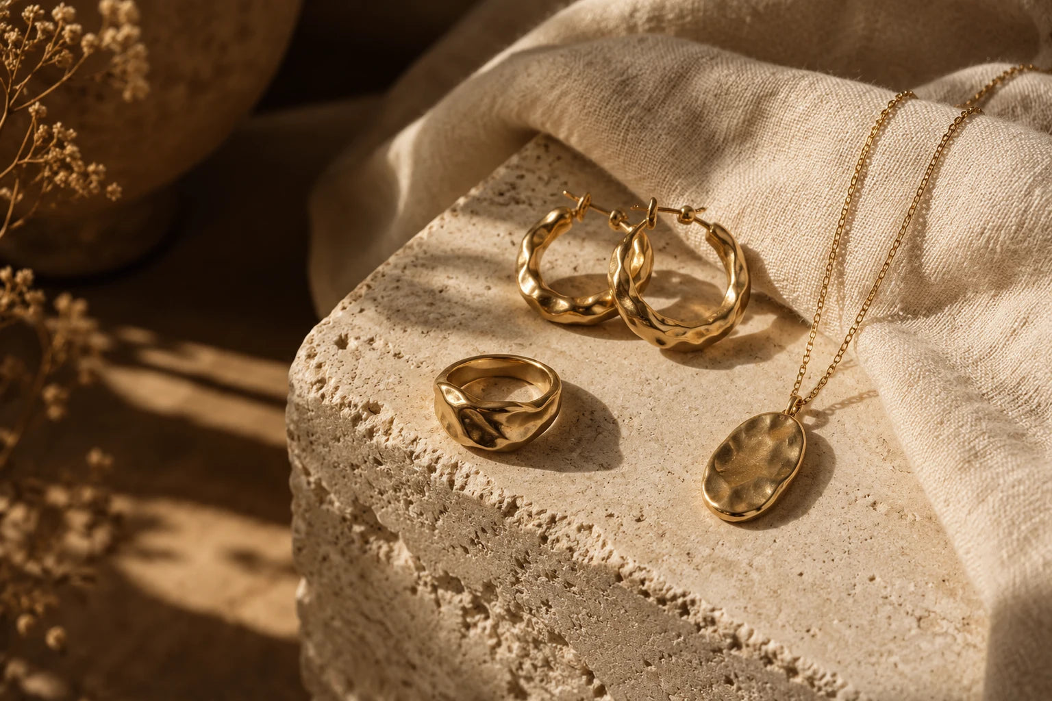 Composition de bijoux dorés sur pierre claire et lin